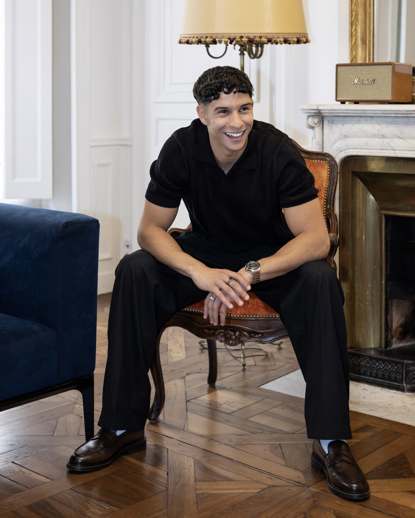 Portrait de Naïm Khelif, assis dans un salon, souriant.